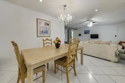 a dining table and chairs in a living room at Canal-Front Gem with Pool 3 Mi to Hard Rock Stadium in Miramar