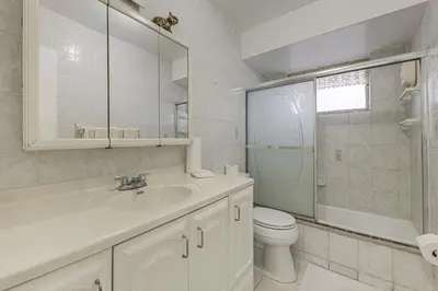 a bathroom with a sink and a toilet and a mirror at Canal-Front Gem with Pool 3 Mi to Hard Rock Stadium in Miramar