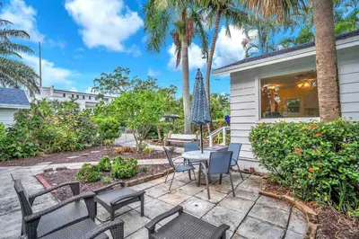 a patio with chairs and a table in front of a house at Bromeliad Bungalow - Downtown Cottage in Fort Lauderdale