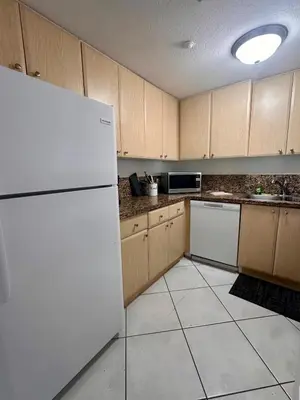 a kitchen with a white refrigerator and wooden cabinets at Beautiful 2brm condo w free parking fast WiFi in Lindgren Acres