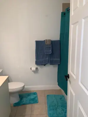a bathroom with a toilet and two blue towels at Miami Fort Lauderdale Vacation Rooms in Miramar