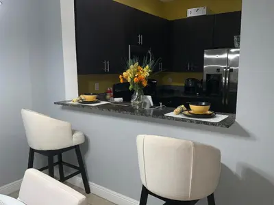 a kitchen with two stools and a counter with two chairs at Miami Fort Lauderdale Vacation Rooms in Miramar