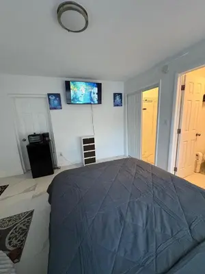 a bedroom with a bed with a tv on the wall at Family Willy Michel in Opa-locka