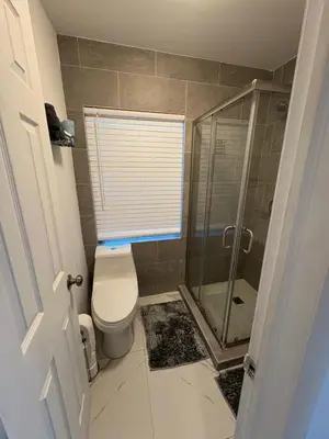 a bathroom with a toilet and a glass shower at Family Willy Michel in Opa-locka