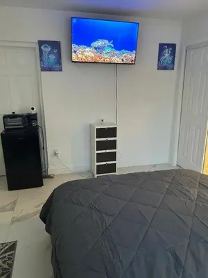 a bedroom with a bed and a flat screen tv on the wall at Family Willy Michel in Opa-locka