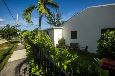 a white house with a palm tree and a fence at The Side Villa in Miami