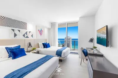 two beds in a hotel room with a view of the ocean at Luxury 2BR Apt With Ocean View Pool & Amenities in Hollywood