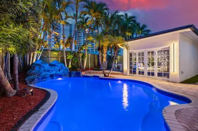 a swimming pool in a backyard with palm trees at Beach Pop - Steps to Beach Heated Pool & Hot Tub in Fort Lauderdale