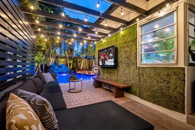 a living room with a couch and a tv at Beach Pop - Steps to Beach Heated Pool & Hot Tub in Fort Lauderdale
