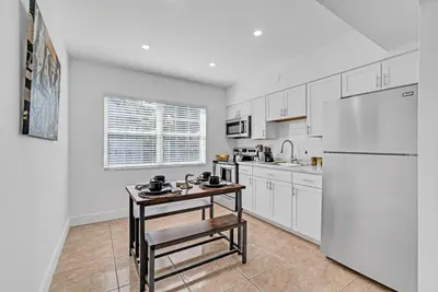 a kitchen with a white refrigerator and a table at Miami Luxury Home Close to Beach & Aventura Mall in Biscayne Park