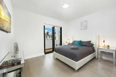 a white bedroom with a bed and a desk and a window at Villa Costa in Hollywood
