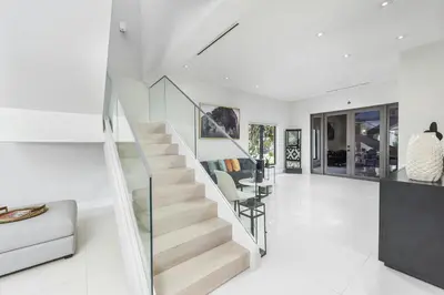 a staircase in a white living room with a glass railing at Villa Costa in Hollywood