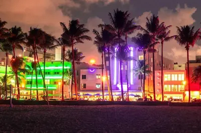 a city with palm trees and a building with lights at Ocean Dr 1BR Apt with Rooftop Pool 93 Walk Score in Miami Beach