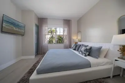 a white bedroom with a large bed and a window at Ocean Drive Retreat - Beach Access & Rooftop Pool in Miami Beach