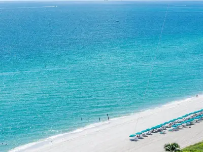 an aerial view of a beach with chairs and the ocean at Lovely 2-Bedroom Oceanfront condo in Sunny Isles Beach