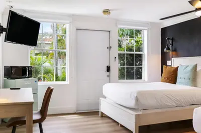 a bedroom with a bed and a desk and a tv at The Victoria Hotel in Fort Lauderdale