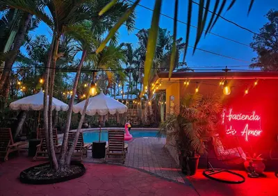 a resort with a swimming pool and a resort with palm trees at Hacienda de Amor - Heated pool - Hot Tub - Firepit in Fort Lauderdale