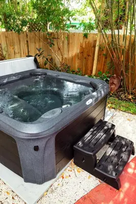 a large hot tub with a bench in a yard at Hacienda de Amor - Heated pool - Hot Tub - Firepit in Fort Lauderdale