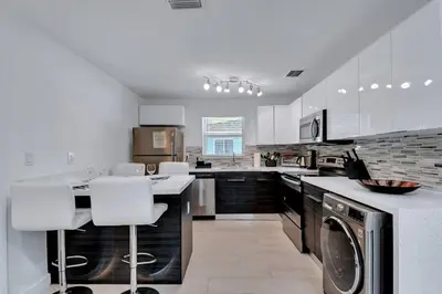 a kitchen with white cabinets and a washer and dryer at Stylish 2BR Retreat in Miamis Design District in Miami