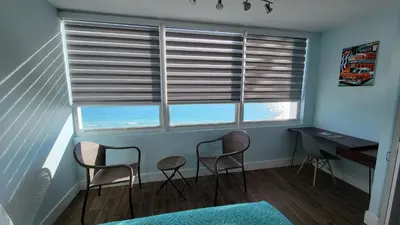 a room with three chairs and a desk and windows at Amazing ocean view studio 14 floor Free parking in Miami Beach
