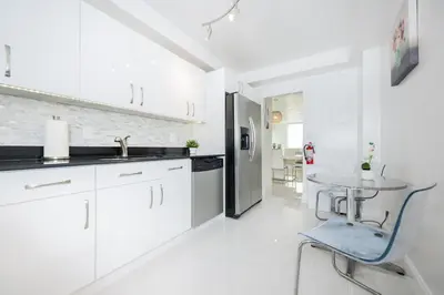 a white kitchen with a table and a blue chair at Hollywood Beachfront 2-Bedroom Condo with Ocean Views in Hollywood