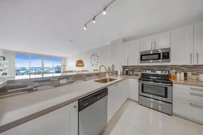 a white kitchen with a sink and a stove at Waterfront 2BR Unit with Bayview Boho Style Stunning Sunset Pool Hot Tub Gym in Sunny Isles Beach