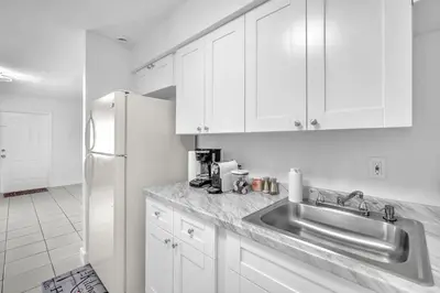 a white kitchen with a sink and a refrigerator at Costerra Miami 2BR in Miami