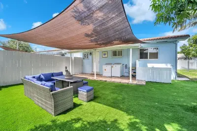 a patio with a couch and a table on a lawn at Costerra Miami 2BR in Miami