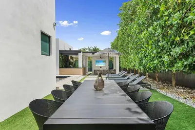 a long long table with chairs and an umbrella at Villa Coral Wave in Miami