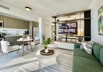 a living room with a green couch and a kitchen at SPECIAL OFFER - Luxury High Rise Downtown Miami - Bay Views and Top Amenities in Miami