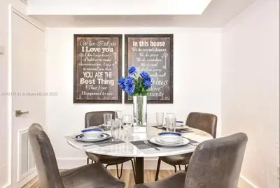 a dining room with a table with a vase of blue flowers at North Beach-Room with Private Entrance in Miami Beach