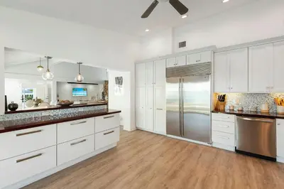 a kitchen with white cabinets and a stainless steel refrigerator at Villa Tropique in Miami Beach