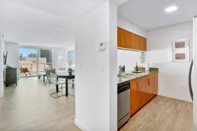 a kitchen with white walls and wooden cabinets and a table at Brickell Bay Condo with Views plus Parking Sleeps 6 in Miami