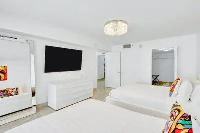 a white bedroom with a bed and a flat screen tv at Stylish Brickell Condo with Balcony and Parking in Miami