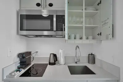 a white kitchen with a sink and a microwave at Modern Comfort Steps from the Ocean Breeze in Miami
