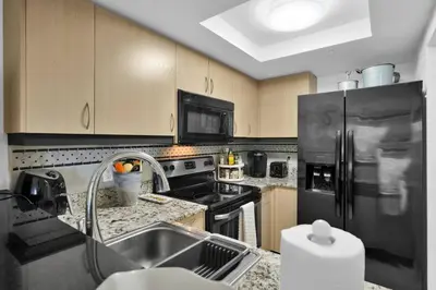 a kitchen with a sink and a black refrigerator at Bayshore Charm-Free Parking in Miami