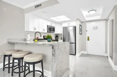 a kitchen with white cabinets and bar stools at Palm Oasis, Pool and Free Parking in Miami