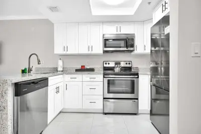 a kitchen with white cabinets and stainless steel appliances at Palm Oasis, Pool and Free Parking in Miami