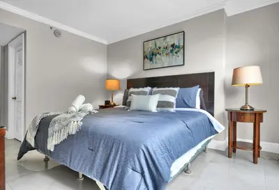 a bedroom with a bed with a blue comforter at Palm Oasis, Pool and Free Parking in Miami