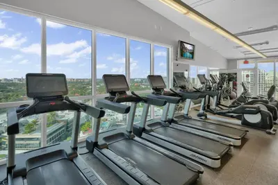a gym with a row of treadmills and elliptical machines at Grove Escape-Ocean Glimpse in Miami