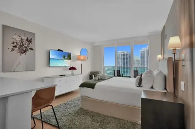 a bedroom with a bed and a desk with a television at The Harmony - Ocean and Relaxation in Miami