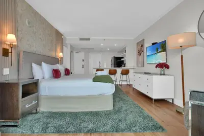 a bedroom with a large white bed and a kitchen at The Harmony - Ocean and Relaxation in Miami