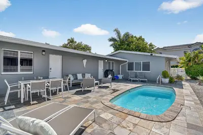 a backyard with a pool and a table and chairs at Victoria Park's Secret Estate in Fort Lauderdale