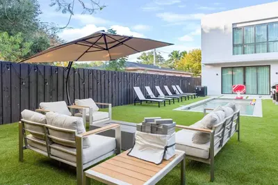 a patio with chairs and an umbrella in a yard at 3BR Vibrant Havana Villa in Miami, Pool, Grill, Backyard in Miami