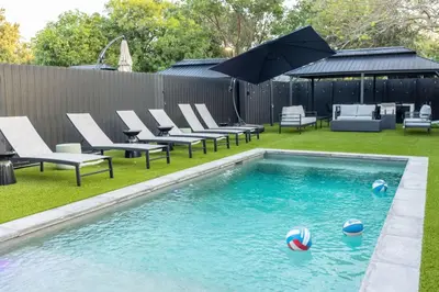 a swimming pool with chairs and an umbrella in a yard at Parisian Vibe in Design District Miami with Private Pool BBQ Spacious Backyard in Miami