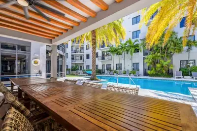 an outdoor dining area with a wooden table and a swimming pool at Aqua Luxe in DTWN 3 Min From Las Olas in Fort Lauderdale