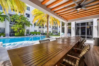 a dining room with a wooden table and a pool at Isla Blue in DTWN 3 Min From Las Olas in Fort Lauderdale