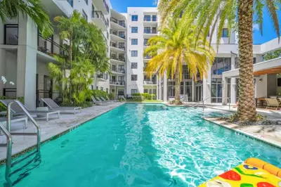 a swimming pool with palm trees and a building at Prestige Living in DTWN 3 Min From Las Olas in Fort Lauderdale