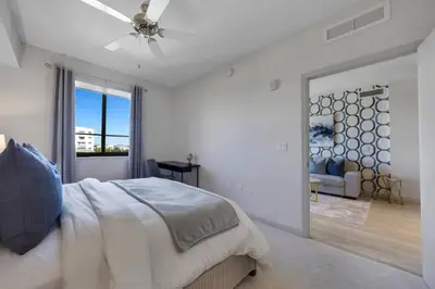 a white bedroom with a bed and a living room at Serene Bleu in DTWN 3 Min From Las Olas in Fort Lauderdale
