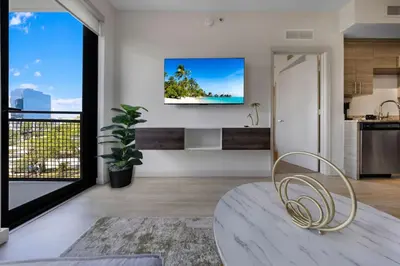a living room with a tv on the wall and a chair at Coral Haven in DTWN 3 Min From Las Olas in Fort Lauderdale